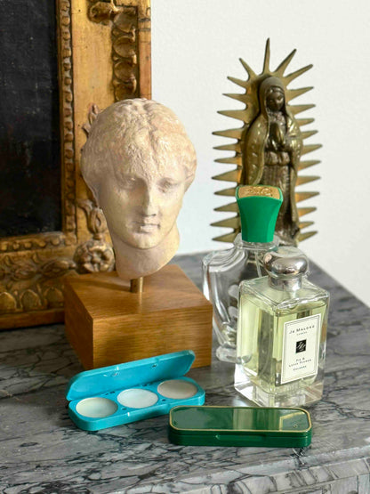 Vintage-style items including a bust, framed picture, and perfume bottles on a marble surface.